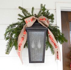 a lantern hanging from the side of a house with a bow on it's front door