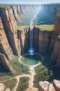 an aerial view of a large waterfall in the middle of a canyon with people walking around it