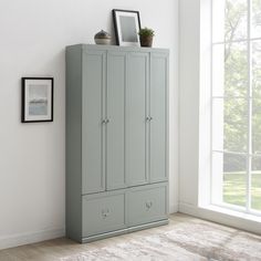 an empty room with a large gray cabinet next to a window and pictures on the wall