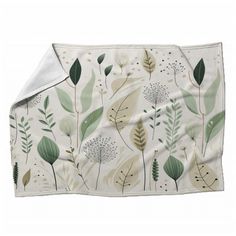 a white blanket with green leaves and plants on the front is folded in half to show an inner corner