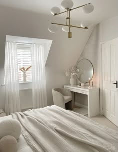 a bedroom with a bed, desk and mirror in the corner next to a window