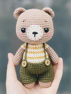 a small crocheted teddy bear wearing overalls and a striped t - shirt