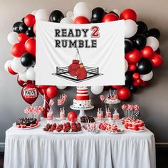 a table topped with cake and balloons next to a sign that reads ready rumble 2