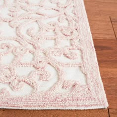 a pink and white rug on top of a wooden floor