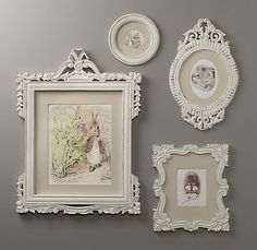 an assortment of framed pictures on a gray wall with white trimmings and ornate frames