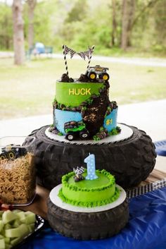 a monster truck themed birthday cake on top of a table with other desserts and snacks