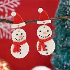 two snowman earrings hanging from a tree branch