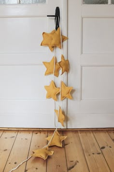 some yellow stars are hanging from a door handle on a wooden floor in front of a white door