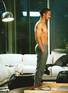 a shirtless man standing in the middle of a living room next to a couch