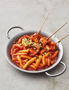 a pan filled with pasta covered in sauce and topped with meatsticks on top of a table