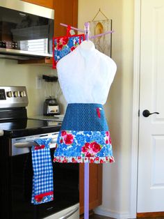 a dress on display in a kitchen with an oven and microwave behind it that is decorated with red, white and blue flowers