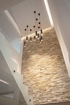 an open staircase leading up to the top floor in a modern home with stone walls and ceiling lights