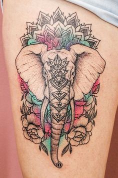 an elephant tattoo on the side of a woman's thigh with flowers around it