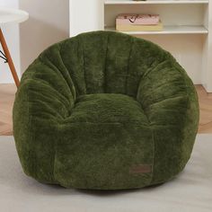 a green bean bag chair sitting on top of a carpeted floor next to a book shelf