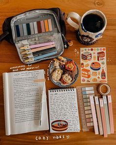 an open book, cup of coffee, pencils and other items on a table