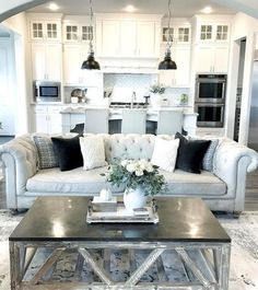 a living room filled with furniture and a kitchen in the backgroung area