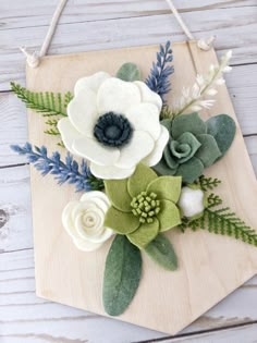 a wooden board with flowers on it and green leaves around the edges, hanging from a rope