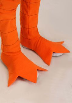 the legs and feet of a person wearing orange shoes with shark claws on them,