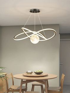 a dining room table and chairs with a light fixture above it that is suspended from the ceiling