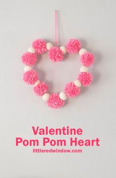 valentine pom - pom heart ornament hanging on a wall with text overlay