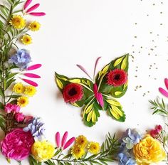 colorful flowers and butterflies are arranged on a white surface