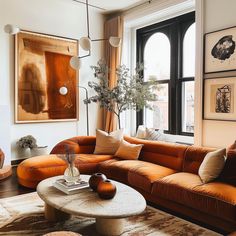 a living room with orange couches and pictures on the wall above them, along with a coffee table