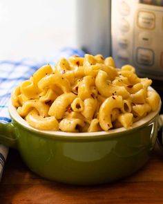 a green bowl filled with macaroni and cheese next to an instant pressure cooker