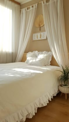 a white bed sitting under a window next to a potted plant