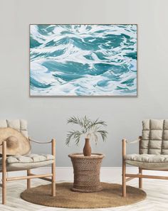 a living room with two chairs and a painting on the wall above it that has blue waves