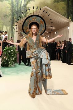 a woman in an elaborate dress and hat walks down the runway at a fashion show