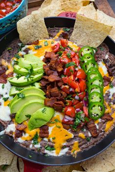 a pan filled with tortilla chips, salsa and sliced jalapenos