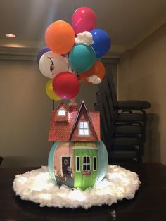 a house with balloons floating above it on top of a cloud filled table in front of a movie theater