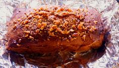 a loaf of bread sitting on top of tin foil covered in nuts and other toppings