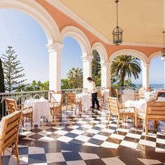 an outdoor dining area with tables and chairs on a checkered floor, overlooking the ocean