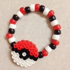 a bracelet made out of legos is shown on a table with white, black and red beads