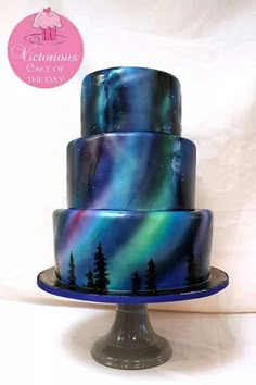 a three tiered cake with an aurora bore pattern on the top and trees on the bottom