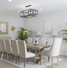 a dining room table with white chairs and a chandelier hanging from the ceiling