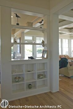 a living room filled with furniture next to a window covered in white bookshelves