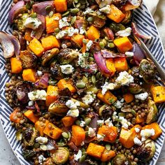 a platter filled with roasted vegetables and feta cheese on top of lentils