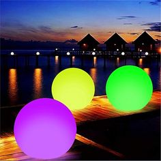 three glowing balls sitting on top of a wooden pier