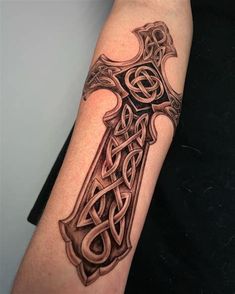 a tattoo on the arm of a person with a cross and celtic knotwork design