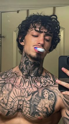 a man with tattoos on his chest brushing his teeth