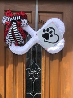 a dog's paw is on the front door with a red and black bow