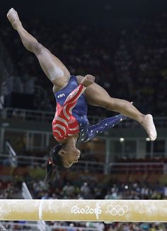 a woman doing a handstand on the balance beam