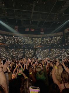 a crowd of people at a concert taking pictures with their cell phones in front of them