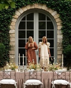 two women standing in front of a table with chairs