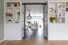 an open door leading to a dining room and living room with white bookcases