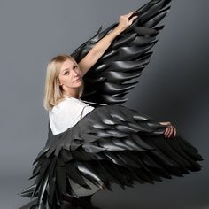 a woman in white shirt and black wings posing for photo with grey background by photographer