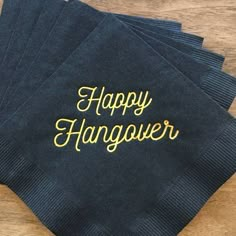 four black napkins with yellow lettering on them sitting on top of a wooden table