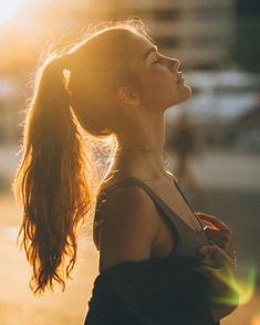 a woman standing on the street with her eyes closed and looking up at the sky